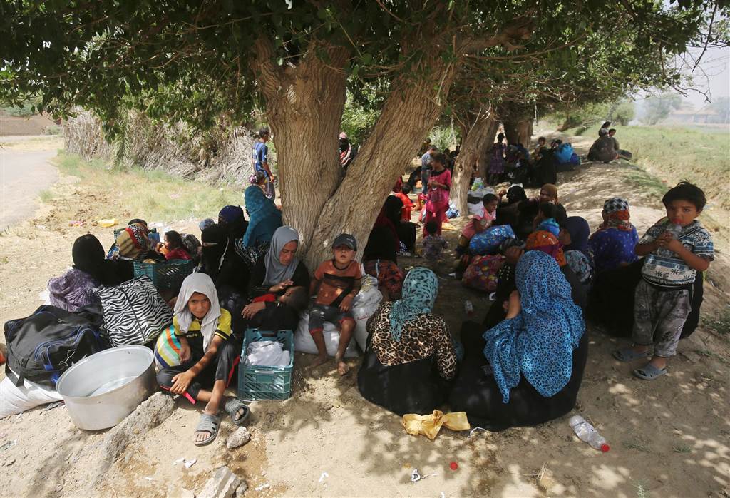Displaced Iraqis, who fled the al-Falahat village west of Fallujah, wait to receive food and aid at the village of al-Azraqiyah, on June 4